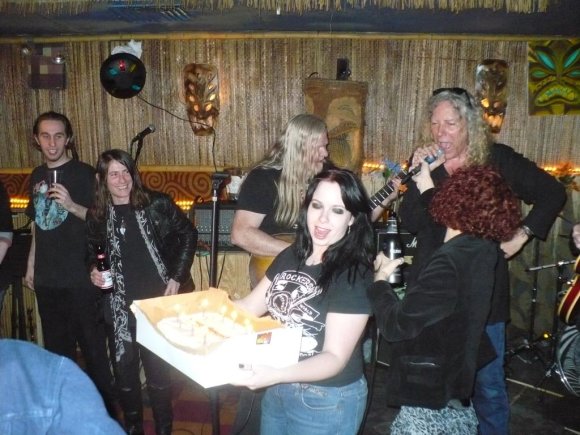 FRANKIE the KID and FUZZ watch as WILD BILL & JOHN perform HAPPY BIRTHDAY as TINA holds the cake.